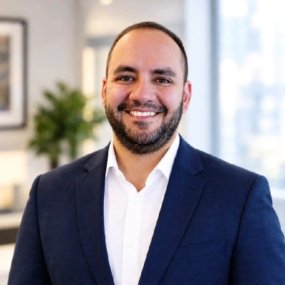 Nima Yasrebi smiling, wearing a navy blazer and white shirt